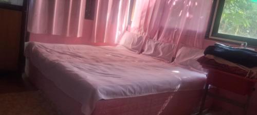 a small bed in a pink room with a window at Shree MAHAGANAPATI ROOMS 6 bed room only for gents in Gokarna