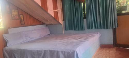 a bed in a room with green curtains at Shree MAHAGANAPATI ROOMS 6 bed room only for gents in Gokarna