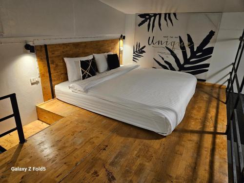 een slaapkamer met een groot wit bed en houten vloeren bij ชวนไดอารี่ Chuan Diary in Ban Nong Bua