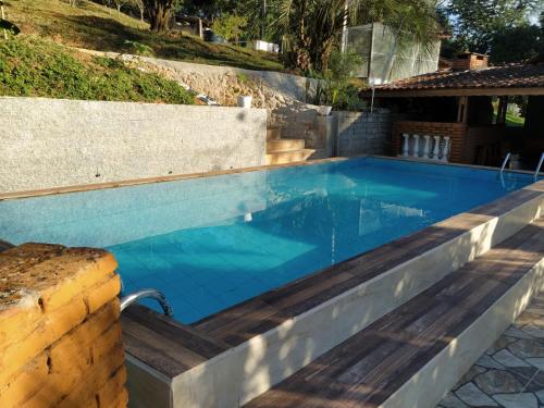 een zwembad met blauw water in een achtertuin bij Sítio Refúgio Primavera in Monte Verde