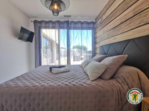 a bedroom with a large bed with a large window at La villa manon in Florensac