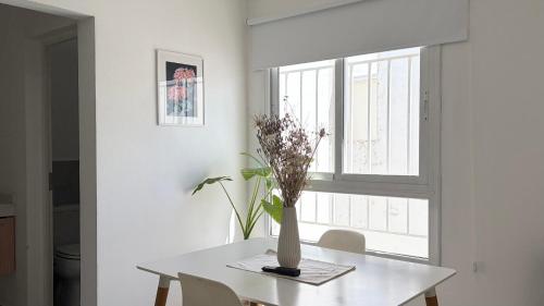 einen weißen Esstisch mit einer Blumenvase darauf in der Unterkunft Temporario Sur, hasta 4 personas con 3 camas, General Roca in General Roca