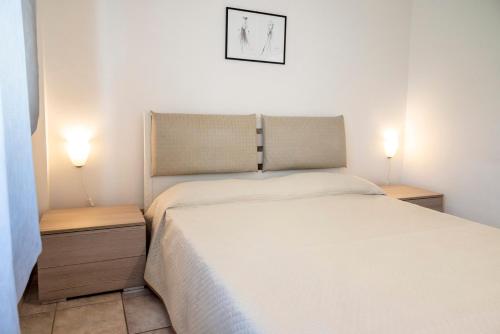 a bedroom with a white bed and two night stands at M377 - Marcelli, bilocale con corte esterna e posto auto in Marcelli