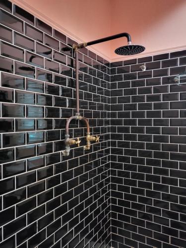 une salle de bain avec un mur carrelé noir avec une douche dans l'établissement Villa Olivia, à Riebeek-Kasteel