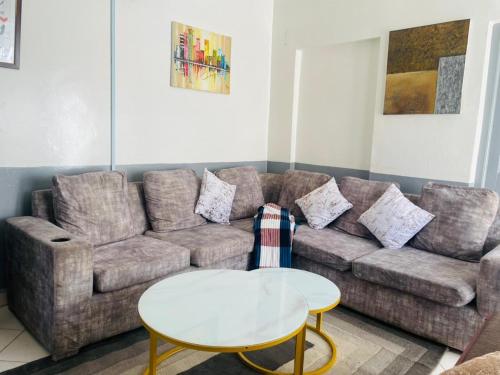een woonkamer met een bank en een tafel bij Le Comfort in Eldoret