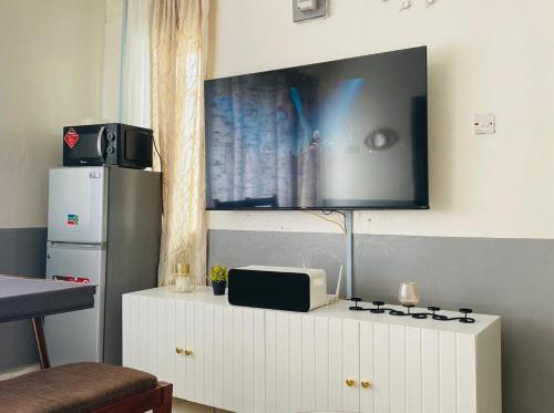 een tv op een witte kast met een magnetron bij Le Comfort in Eldoret