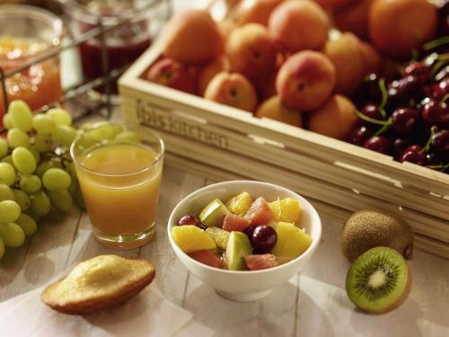 a table with a bowl of fruit and a glass of orange juice at ibis Grenoble Gare in Grenoble