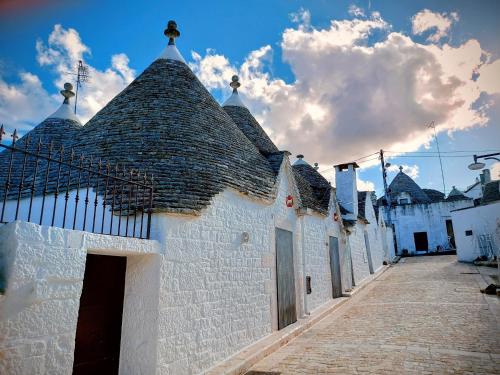 een wit gebouw met een zwart dak op een straat bij il trullo di giada e mattia in Alberobello