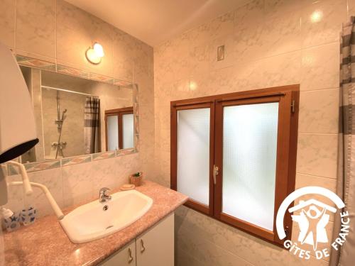 a bathroom with a sink and a mirror and a window at La cave de jean in Gardie