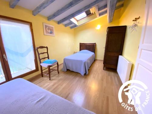 a bedroom with a bed and a chair and a window at La cave de jean in Gardie