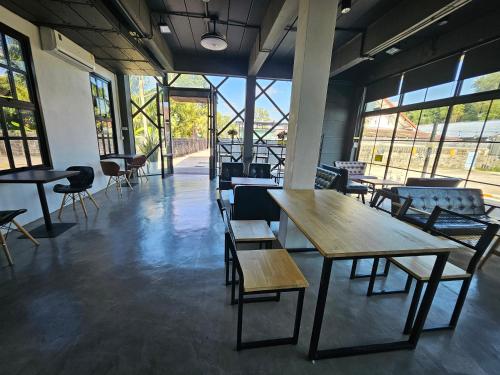 een kamer met tafels, stoelen en ramen bij ชวนไดอารี่ Chuan Diary in Ban Nong Bua