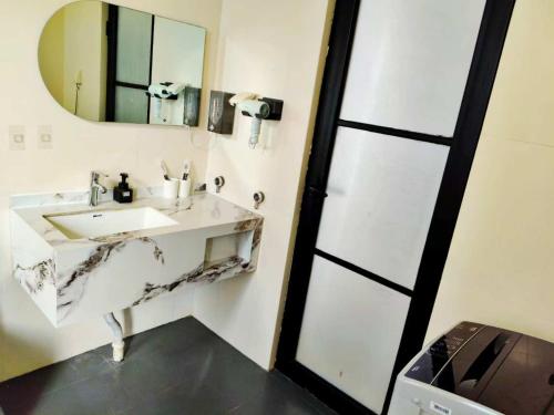 une salle de bains avec un lavabo et un miroir dans l'établissement 闲肆民宿, à Sanya