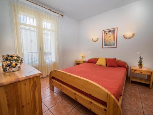 une chambre avec un lit en bois avec un couvre-lit rouge dans l'établissement Bouton d or, à Bolquère-Pyrénées 2000