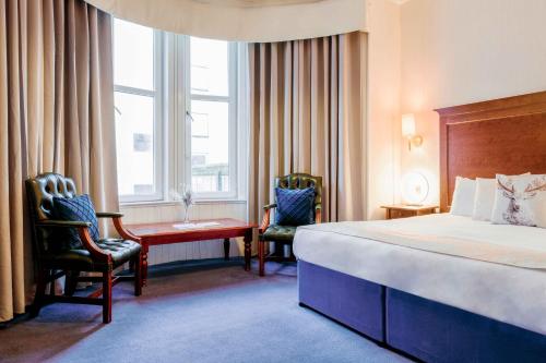 een hotelkamer met een bed en twee stoelen en een bureau bij Muthu Queens Hotel, Oban in Oban