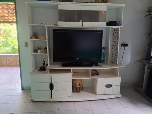 una TV seduta su un centro di intrattenimento bianco di Casa temporada Cavalcante Goiás a Cavalcante