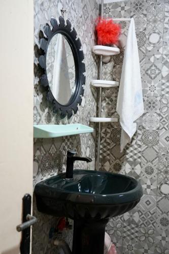a bathroom with a green sink and a mirror at tamazirt surf house in Taghazout