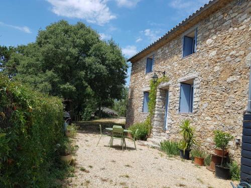 ein Steinhaus mit einem grünen Stuhl davor in der Unterkunft Bergerie du pic saint-loup in Saint-André-de-Buèges