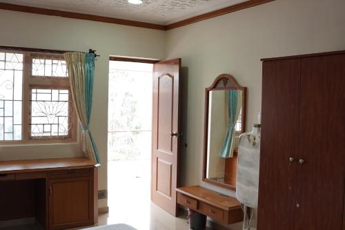 a bathroom with a mirror and a sink and a door at Aarroh villa in Coonoor