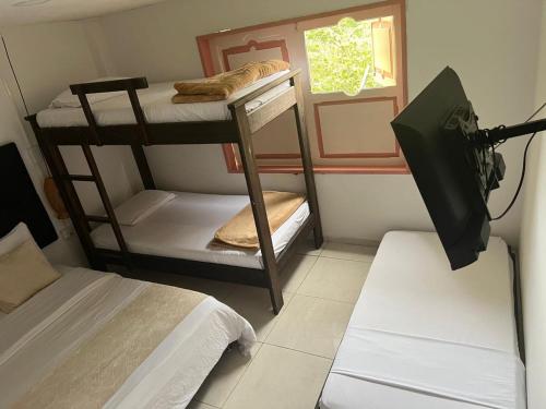 een kleine kamer met twee stapelbedden en een televisie bij Mahalo Hostel in Salento