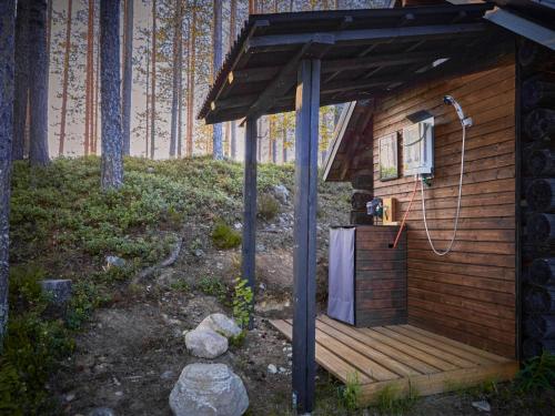 a wooden cabin with a shower on a deck at Capture Nordic Wilderness Camp - Baumzelt in Ilomantsi