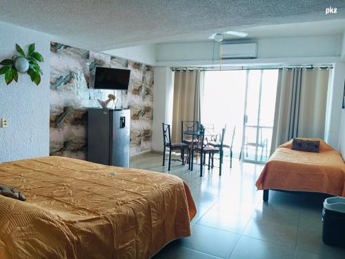 a hotel room with a bed and a table and chairs at SUITE TORRES GEMELAS 2902 vista al mar in Acapulco
