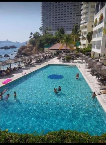 a group of people in a swimming pool at a resort at SUITE TORRES GEMELAS 2902 vista al mar in Acapulco