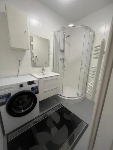 a white bathroom with a washing machine and a shower at Pokoje Metro Imielin in Warsaw