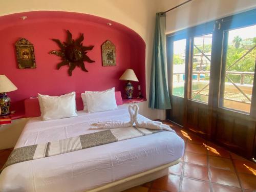 a bedroom with a large bed with a red wall at Regio - Casa MoJo's spacious 2BR, kitchen, pool in Sayulita