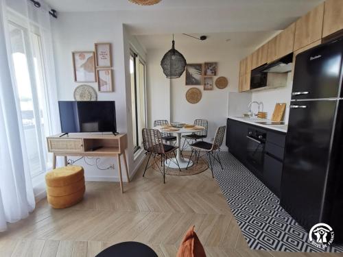 een keuken en eetkamer met een tafel en een zwarte koelkast bij Copatito in Cap d'Agde