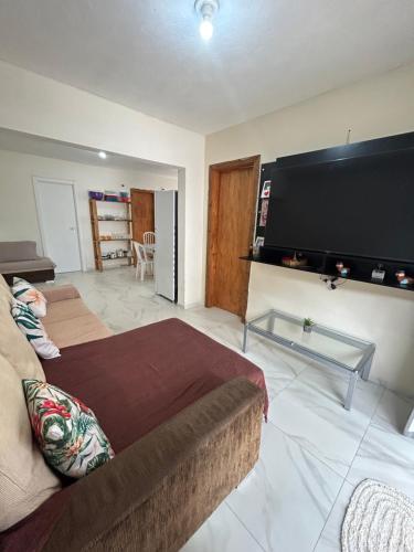 een woonkamer met een bank en een grote flatscreen-tv bij Casa in Bombinhas