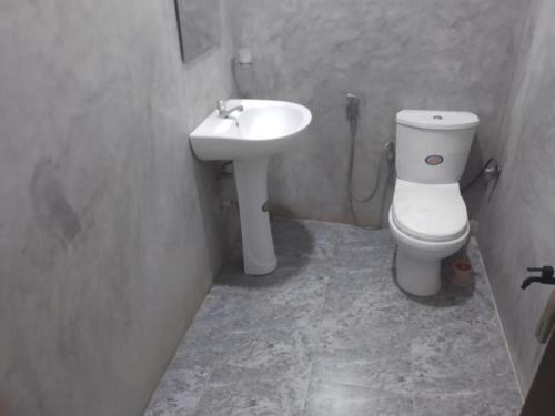 a bathroom with a white toilet and a sink at Orchids Nest Vila Tg in Tangalle