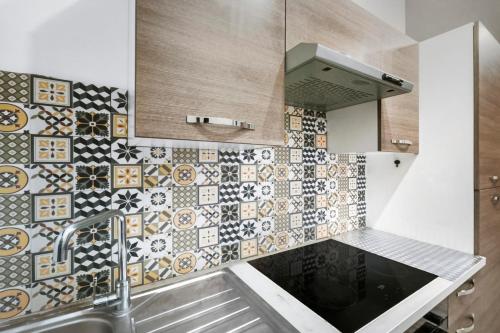 een keuken met een wastafel en een betegelde muur bij T2 moderne avec piscine, terrasse et parking privé in Uzès