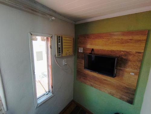 een kamer met een flatscreen-tv en een raam bij Studio Romântico in Volta Redonda