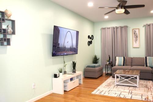 ein Wohnzimmer mit einer Couch und einem Fernseher an der Wand in der Unterkunft Perfect Getaway at CWE- Entire Home with Free Parking Near Fox, Universities and More! in Saint Louis