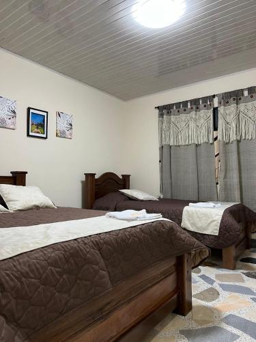 a bedroom with two beds and a window at Hotel Villalva, Cucunuba Cundinamarca in Cucunubá