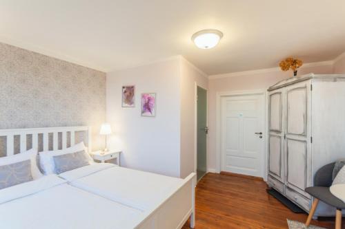 een slaapkamer met een wit bed en een witte deur bij Hotel Villa Wahnfried Thiessow in Thiessow