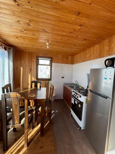 een keuken met een tafel, een koelkast en een fornuis bij Cabañas Vitalis in Curanipe