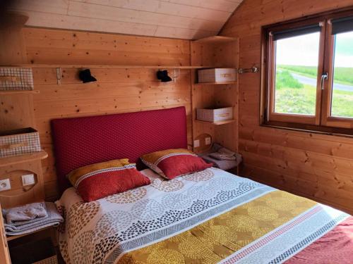 une chambre avec un lit dans une cabane en bois dans l'établissement La roulotte du tonnelier, à Castelnau-de-Montmiral