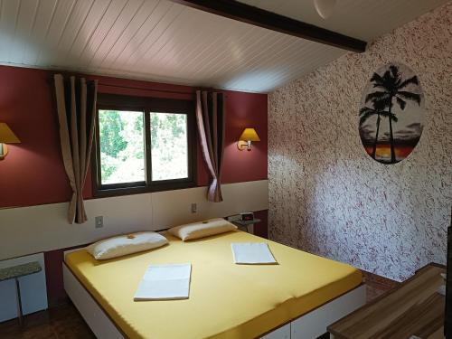 een slaapkamer met een geel bed en een raam bij Pousada Santa Anna in Itaipuaçu