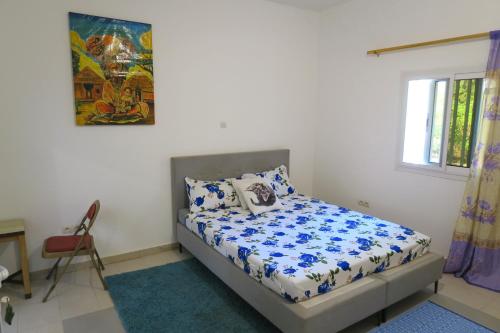 ein Schlafzimmer mit einem Bett mit blau-weißer Bettwäsche in der Unterkunft Chez Fatou et Saladin in Diana