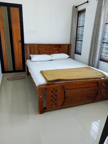 a wooden bed in a room with a window at Nature's View Service Villa in Vythiri