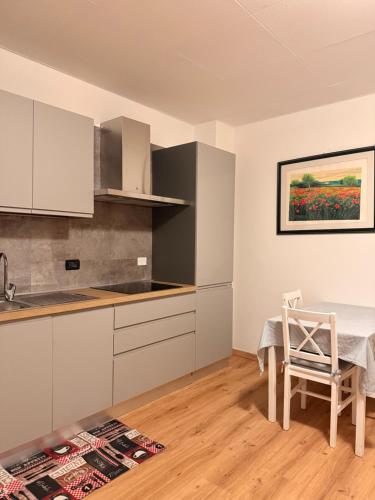 une cuisine avec des armoires blanches et une table et une chaise dans l'établissement Monolocale a Molveno, à Molveno
