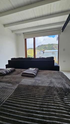 a bedroom with a large bed and a large window at Las Loicas Chalten Apart in El Chalten