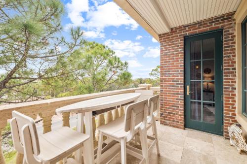 a patio with a table and chairs on a balcony at The Magnolia by 30A Escapes in Rosemary Beach
