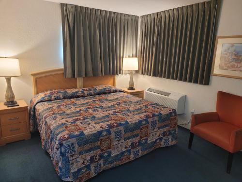 een hotelkamer met een bed en een stoel bij Queens Lodge Motel in West Palm Beach