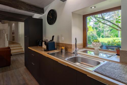 een keuken met een spoelbak en een raam bij Le ruisseau du bejean in Sainte-Gemme