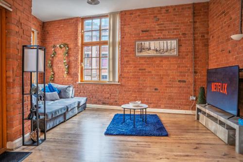 a living room with a couch and a brick wall at City Centre 2-Bed, 2 Balconies, 65 Inch TV, Free Parking, Coffee Machine, Netflix in Leicester