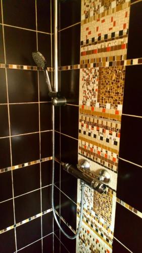 une douche dans une salle de bain avec un mur carrelé dans l'établissement La Sirène Endormie, à Penmarcʼh