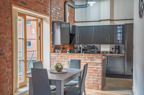 a kitchen with a table and chairs and a brick wall at City Centre 2-Bed, 2 Balconies, 65 Inch TV, Free Parking, Coffee Machine, Netflix in Leicester