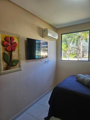 een slaapkamer met een flatscreen-tv aan de muur bij Beach Class Eco Life Figueira in Porto De Galinhas